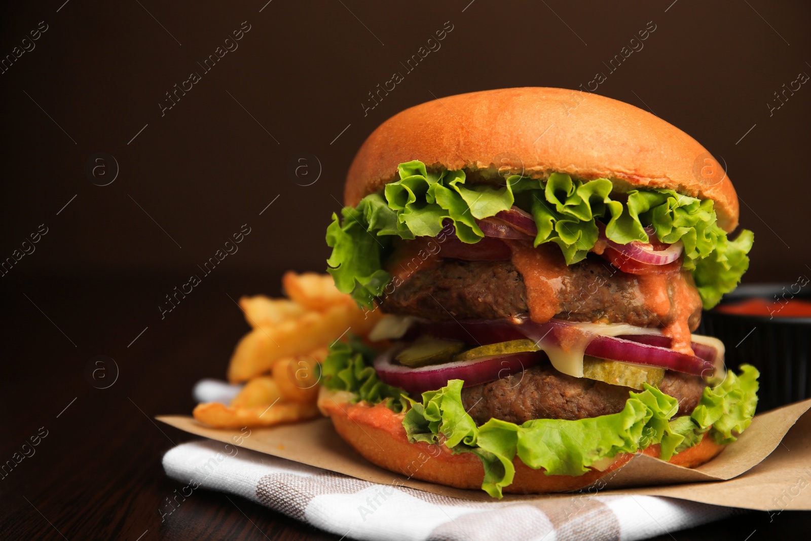 Photo of Tasty burger with vegetables, patties and lettuce served on wooden table, closeup. Space for text