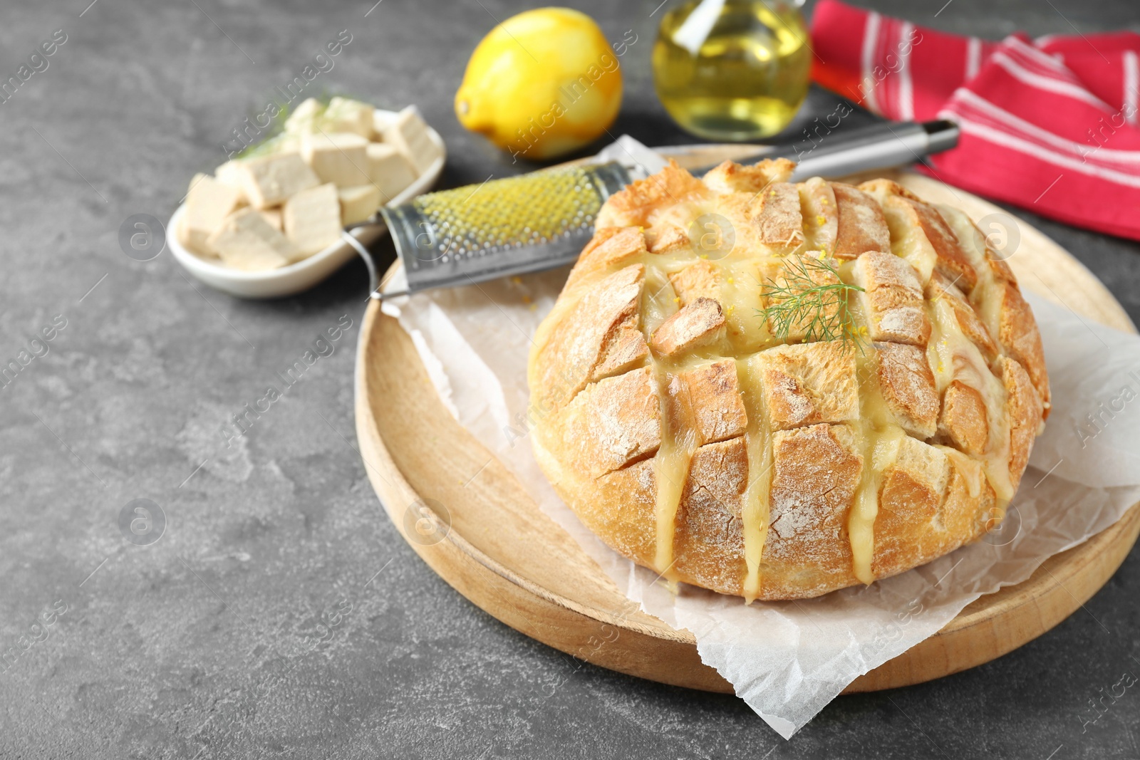 Photo of Freshly baked bread with tofu cheese and lemon zest on grey table