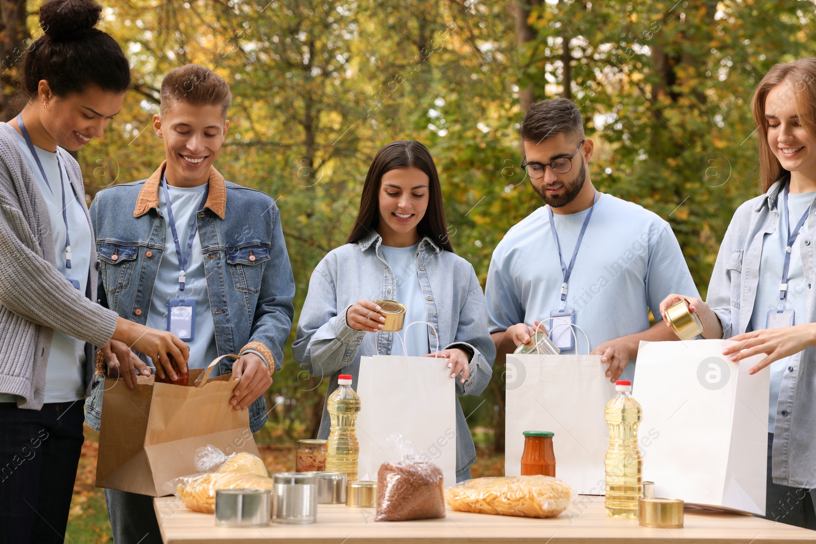 Photo of Group of volunteers packing food products at table in park