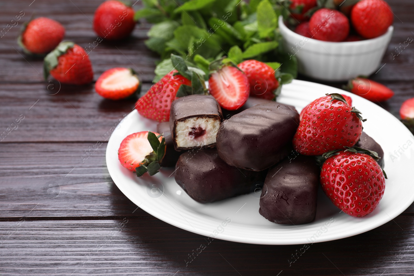 Photo of Delicious glazed curd snacks, mint leaves and fresh strawberries on wooden table. Space for text