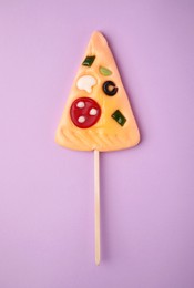 Pizza shaped lollipop on violet background, top view