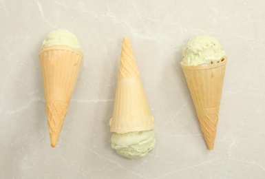 Photo of Delicious pistachio ice cream in wafer cones on light grey table, flat lay