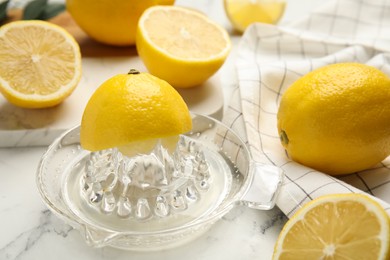 Photo of Glass squeezer and fresh lemons on white marble table