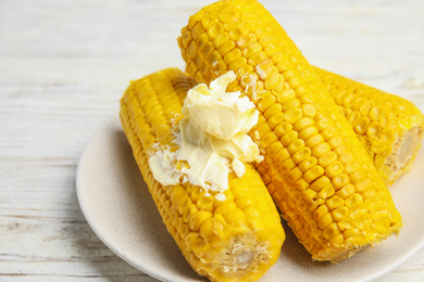 Delicious boiled corn with butter on white wooden table, closeup