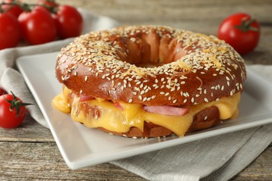 Photo of Delicious bagel with ham and cheese on wooden table