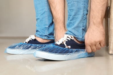 Photo of Man putting on blue shoe covers, closeup