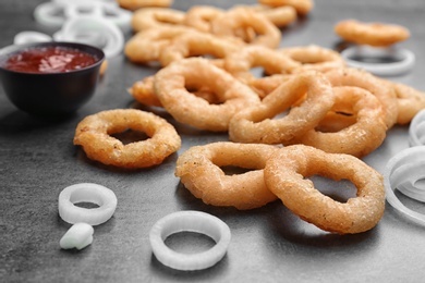 Photo of Raw and fried onion rings on table, closeup