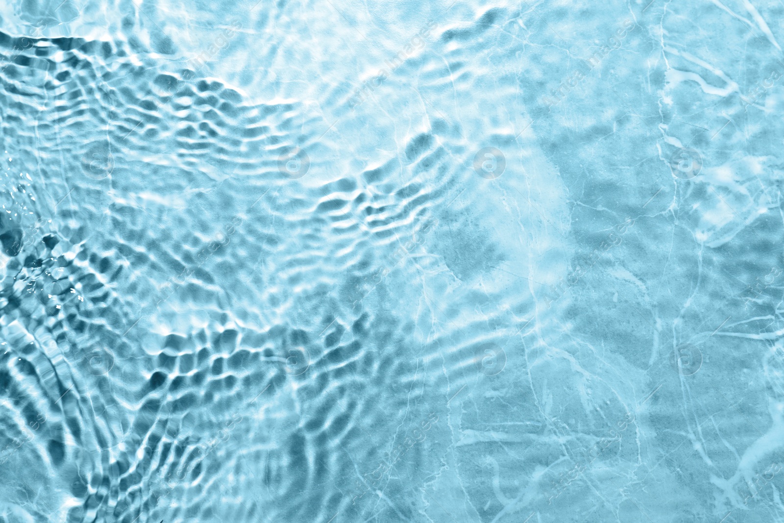 Image of Rippled surface of clear water on light blue background, top view