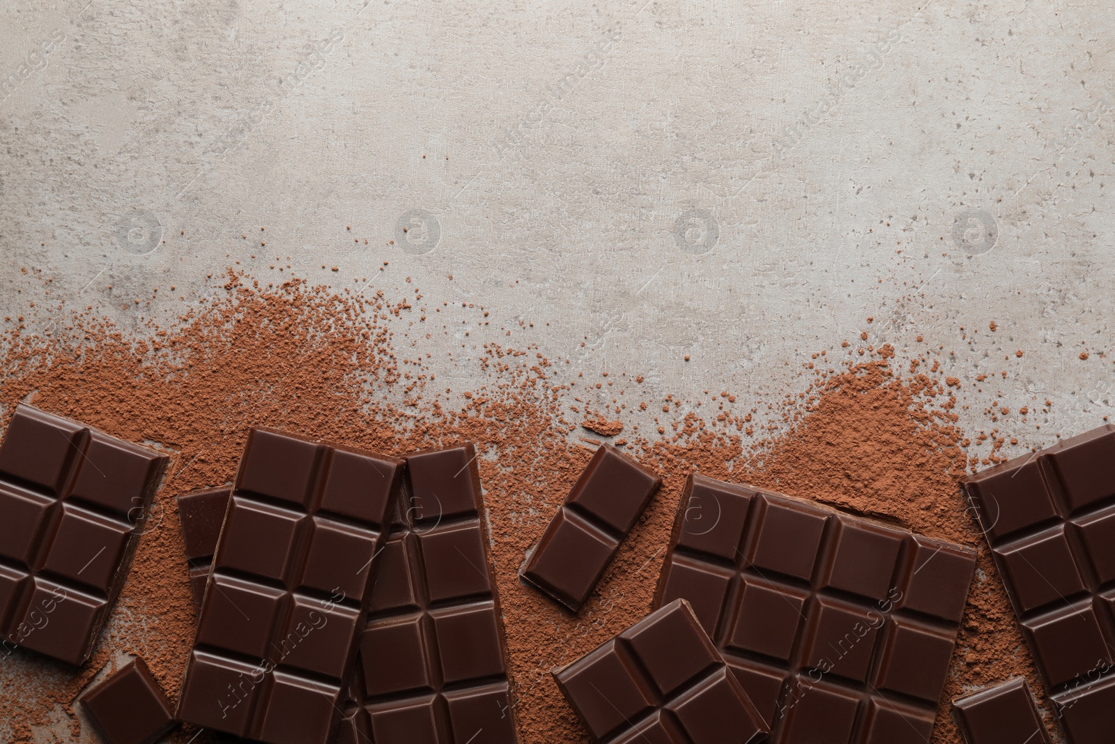 Photo of Delicious dark chocolate and cocoa powder on light grey table, flat lay. Space for text