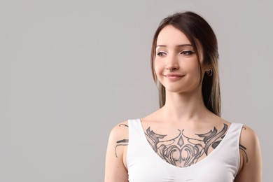 Photo of Portrait of beautiful tattooed woman on grey background. Space for text