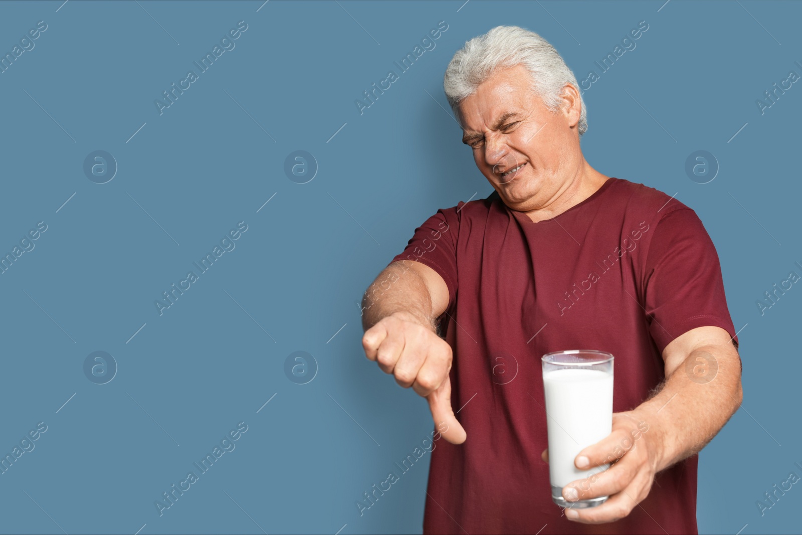 Photo of Mature man with dairy allergy holding glass of milk on color background