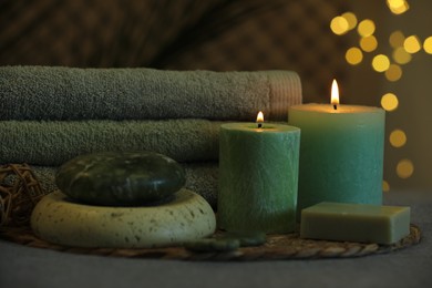 Photo of Spa composition. Burning candles, stones, soap and towels on grey table