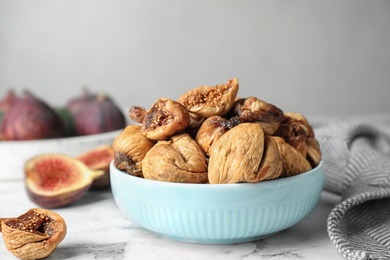 Bowl of tasty dried figs on marble table, closeup