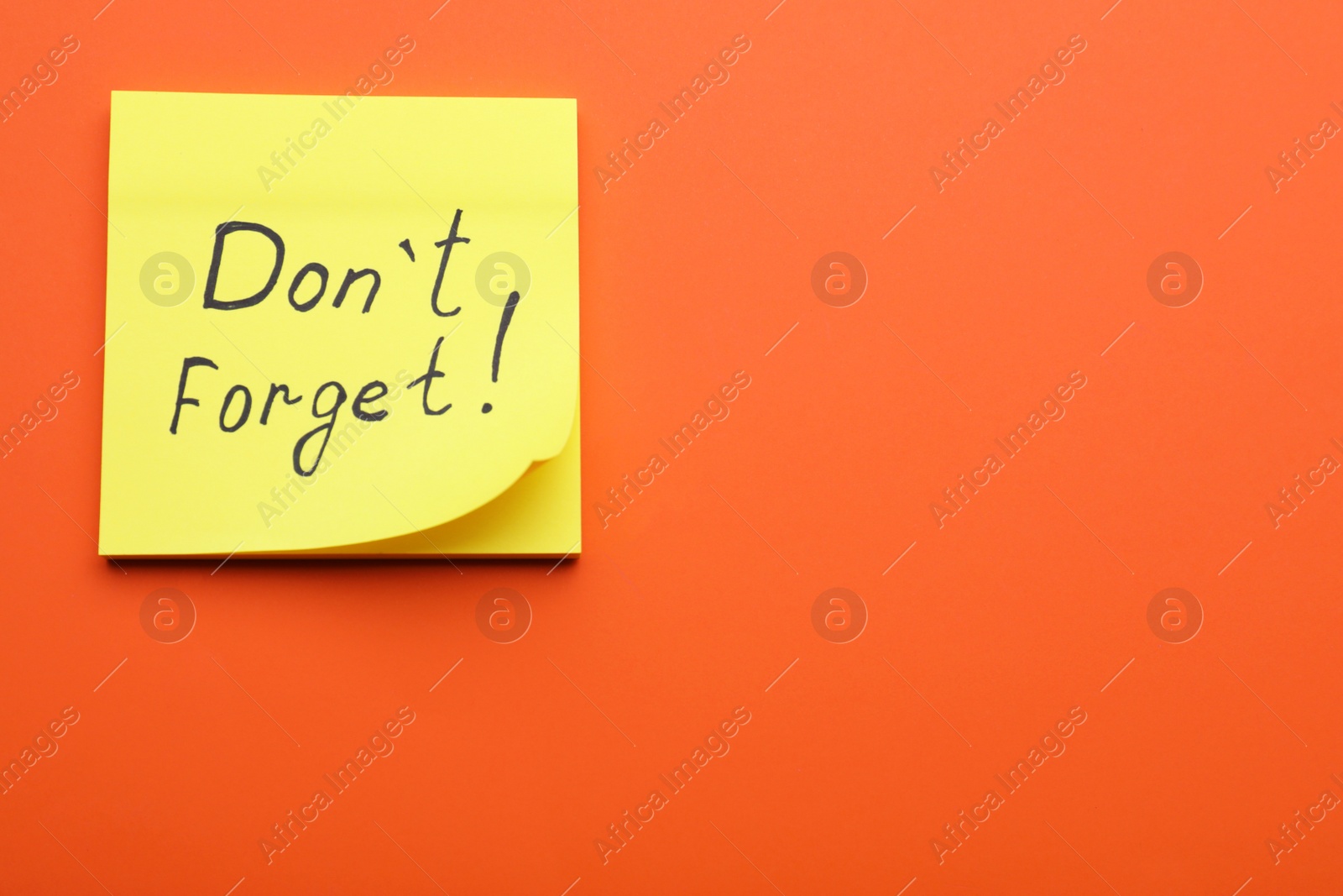 Photo of Paper note with phrase Don t Forget on orange background, top view. Space for text