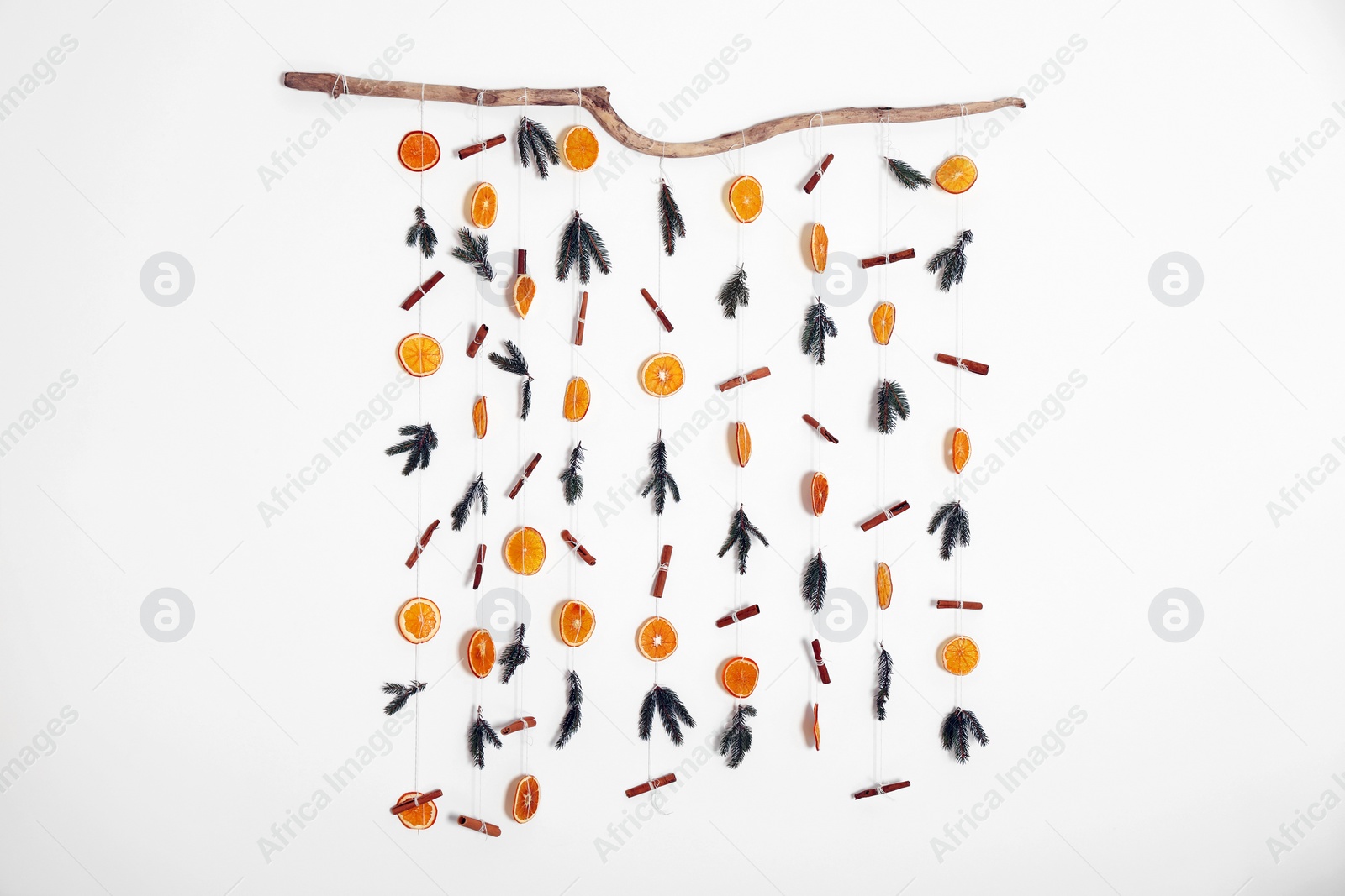 Photo of Handmade decor of dry orange slices, cinnamon sticks and fir tree branches on white wall