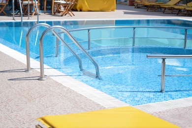 Outdoor swimming pool with ladder and handrails on sunny day