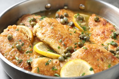 Photo of Delicious chicken piccata with herbs in pot, closeup