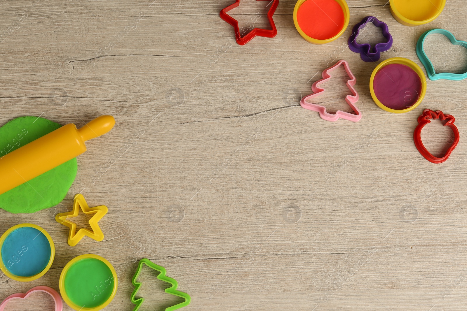 Photo of Different color play dough and tools on wooden table, flat lay. Space for text