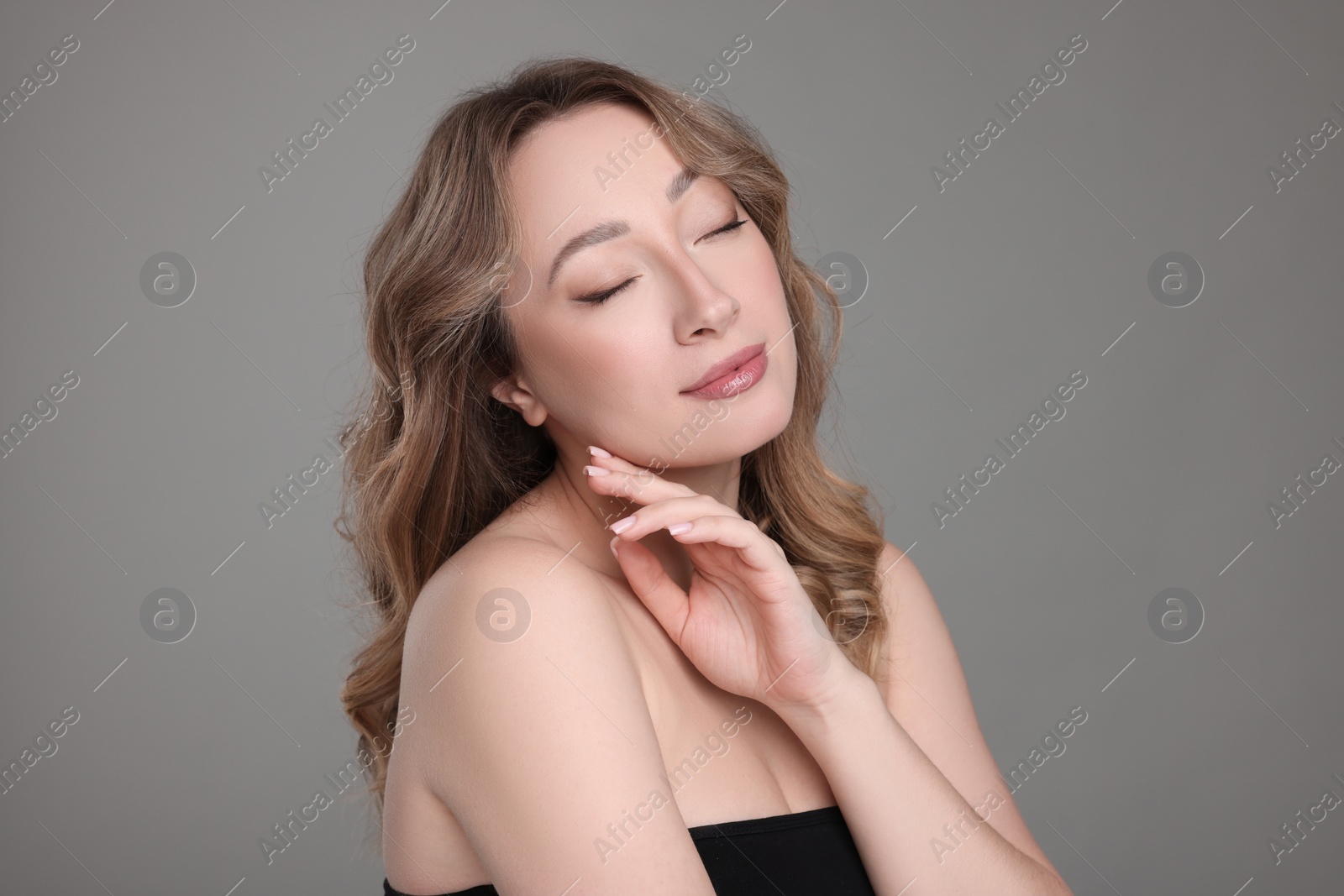 Photo of Portrait of beautiful woman with curly hair on grey background