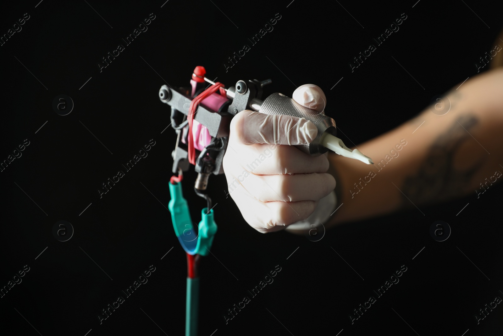 Photo of Tattoo artist with professional machine on black background, closeup