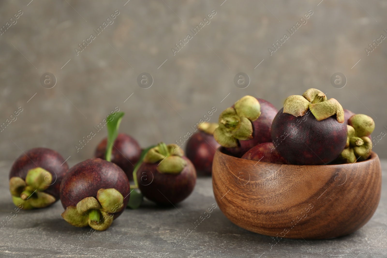 Photo of Fresh ripe mangosteen fruits on grey table. Space for text