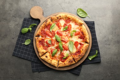 Photo of Delicious Margherita pizza and basil on grey table, top view