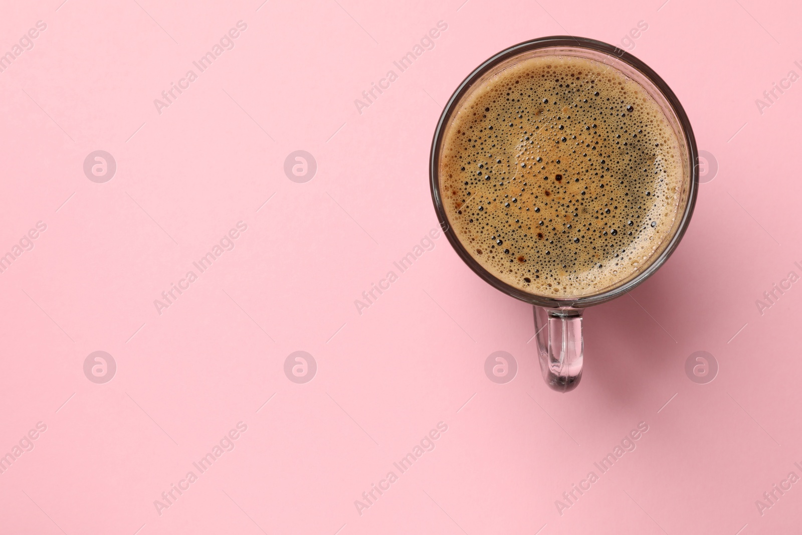 Photo of Aromatic coffee in glass cup on pink background, top view. Space for text