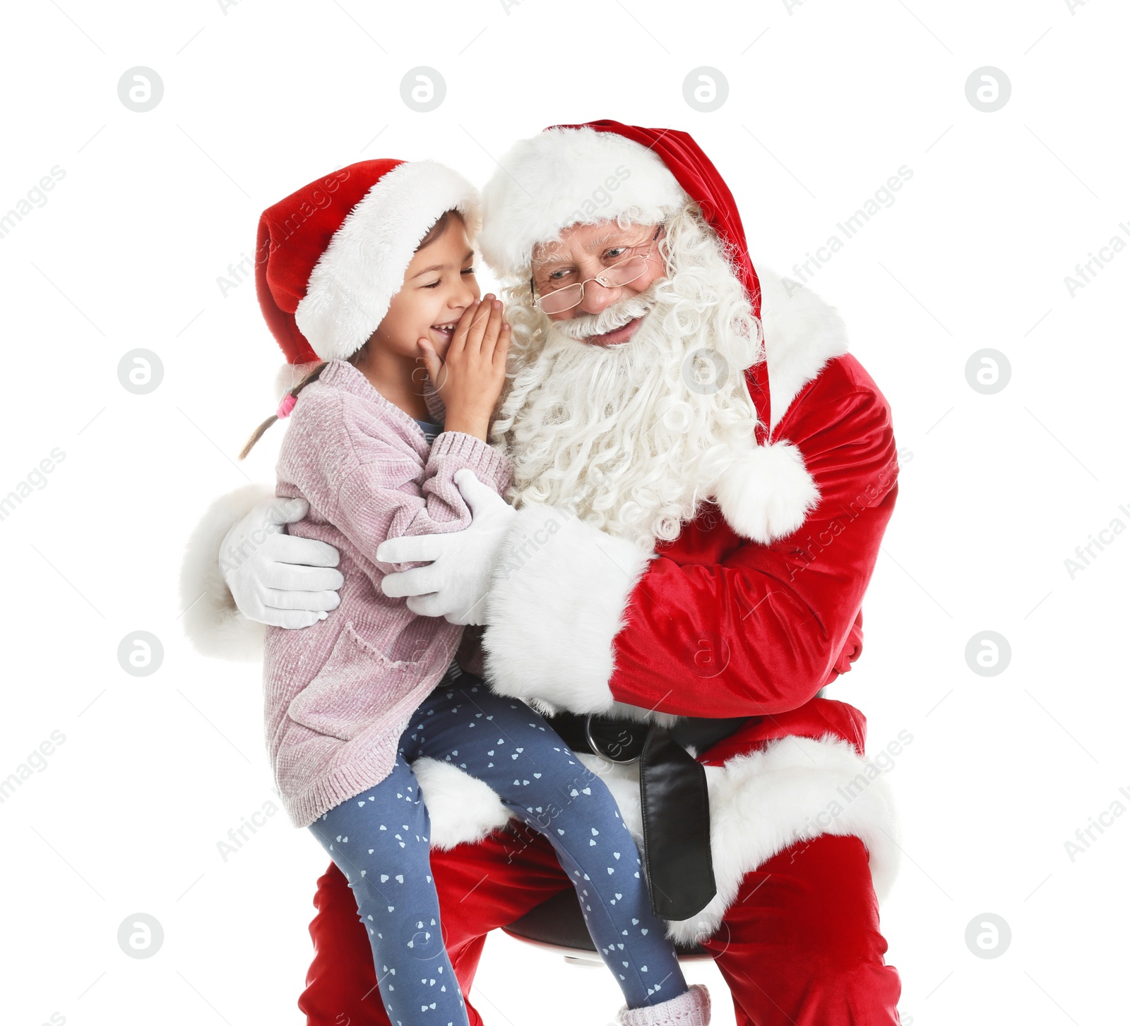 Photo of Little girl whispering in authentic Santa Claus' ear against white background