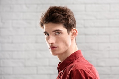 Portrait of young man with beautiful hair on brick wall background