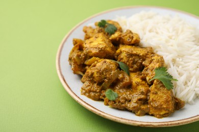 Photo of Delicious chicken curry with rice on green background, closeup