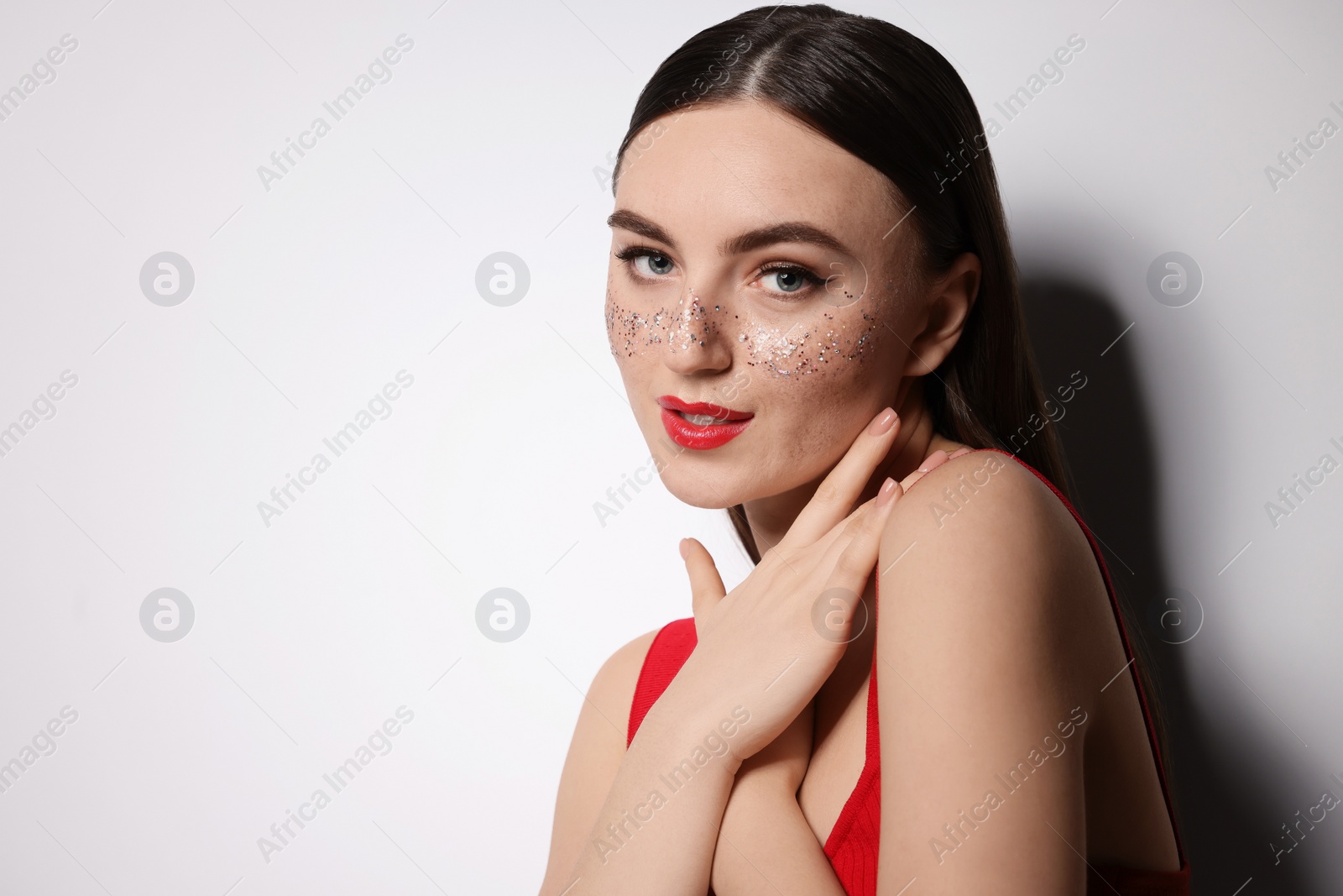 Photo of Beautiful woman with glitter freckles on light background. Space for text