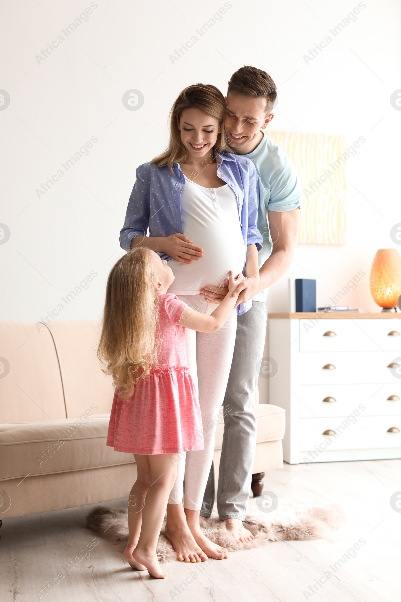 Photo of Young pregnant woman with her family at home