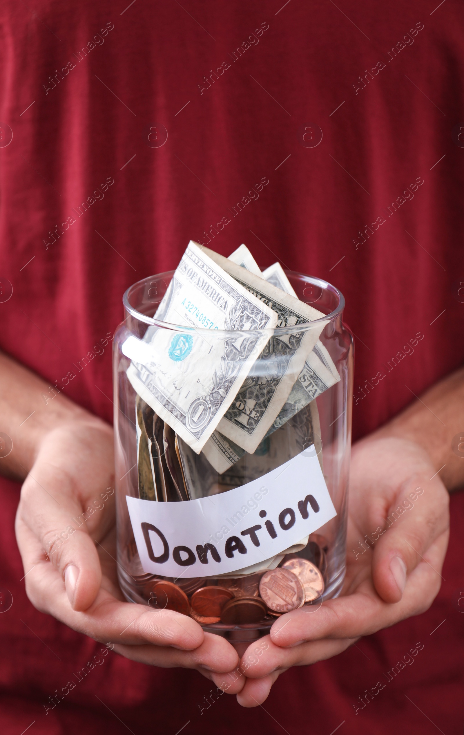 Photo of Man holding jar with money and label DONATION, closeup