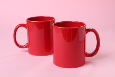 Two red ceramic mugs on pink background