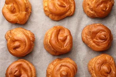 Photo of Delicious profiteroles on parchment paper, flat lay