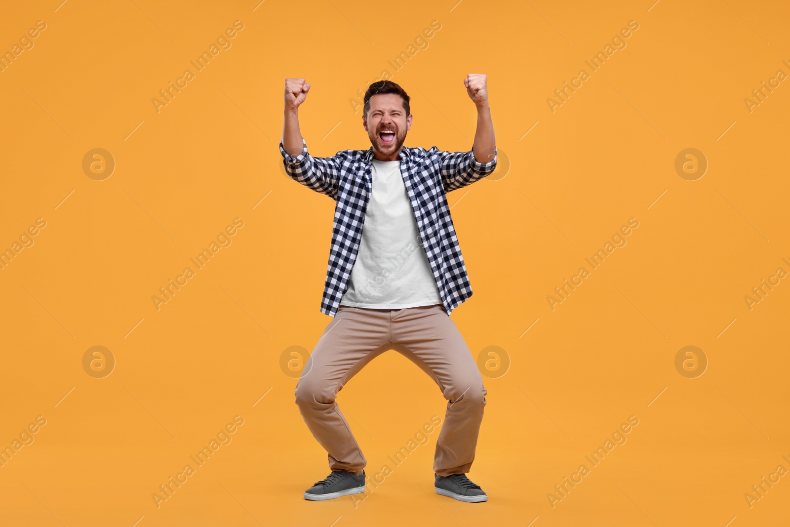 Photo of Emotional sports fan celebrating on yellow background