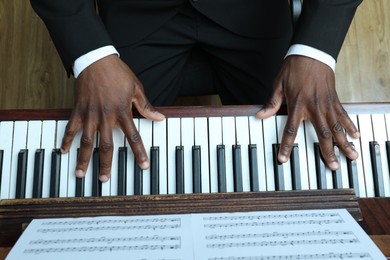 Photo of African-American man playing piano indoors, above view. Talented musician