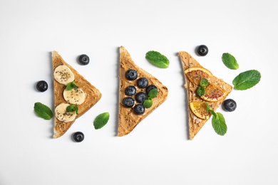Photo of Different toasts with fruits, blueberries, peanut butter and chia seeds on white background, top view