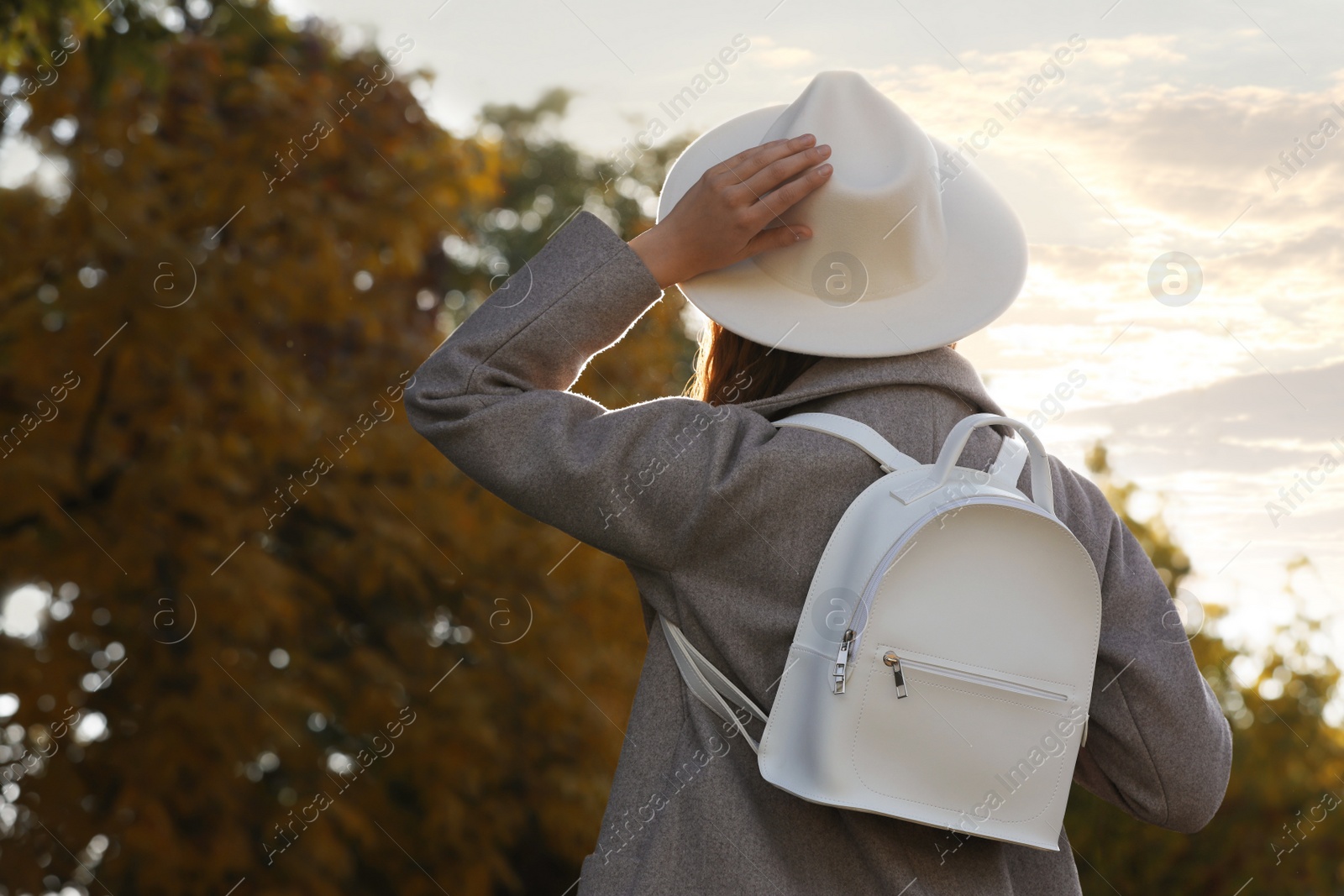 Photo of Young woman with stylish white backpack in park, back view