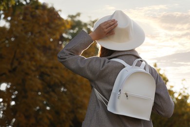 Young woman with stylish white backpack in park, back view