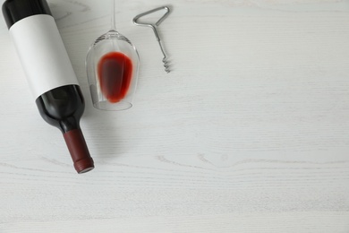 Flat lay composition with bottle of wine and elegant glass on white wooden background. Space for text