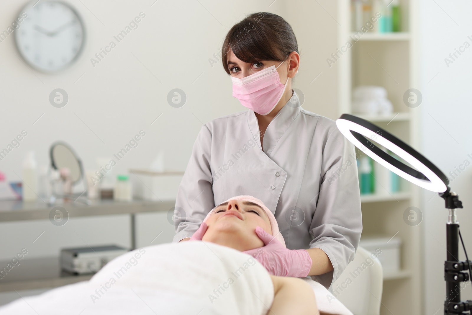 Photo of Cosmetologist making face massage to client in clinic