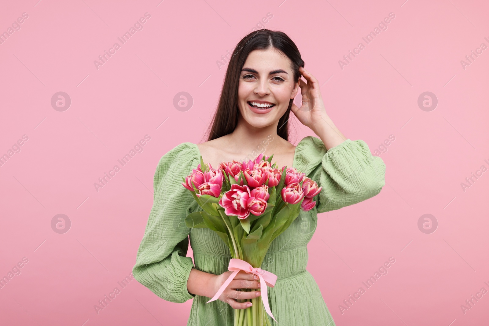 Photo of Happy young woman with beautiful bouquet on dusty pink background