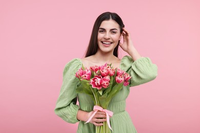 Happy young woman with beautiful bouquet on dusty pink background