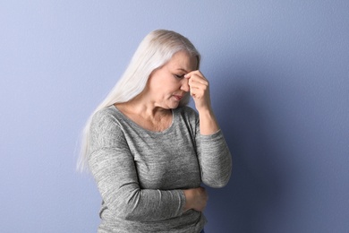 Photo of Mature woman suffering from headache on color background