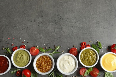 Photo of Bowls with different sauces and ingredients on gray background, flat lay. Space for text