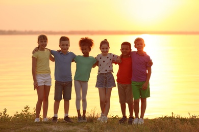 Happy little children near river at sunset