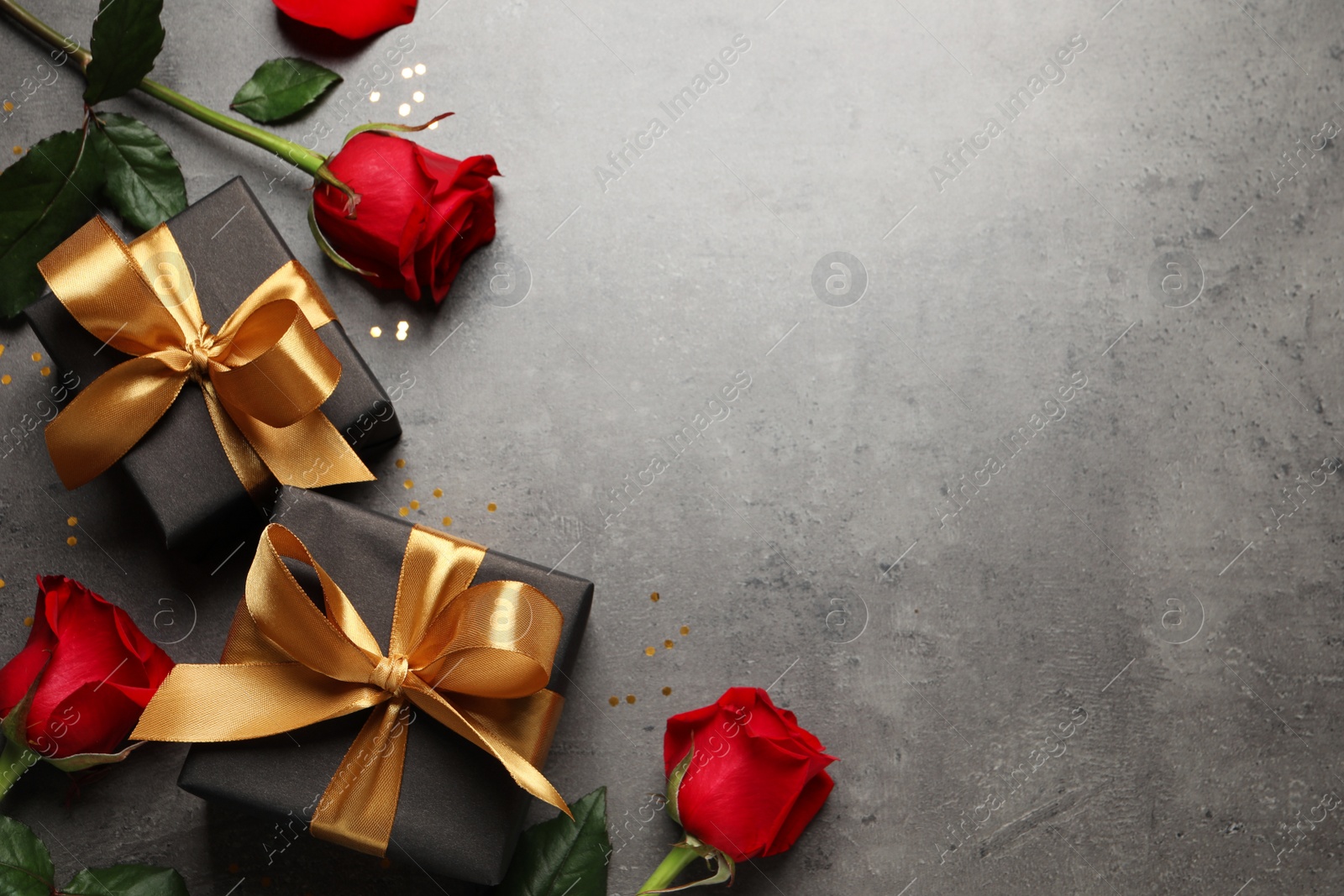 Photo of Two black gift boxes and beautiful roses on dark background, flat lay. Space for text