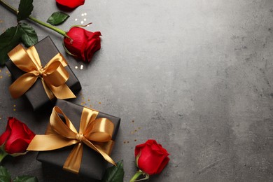 Photo of Two black gift boxes and beautiful roses on dark background, flat lay. Space for text