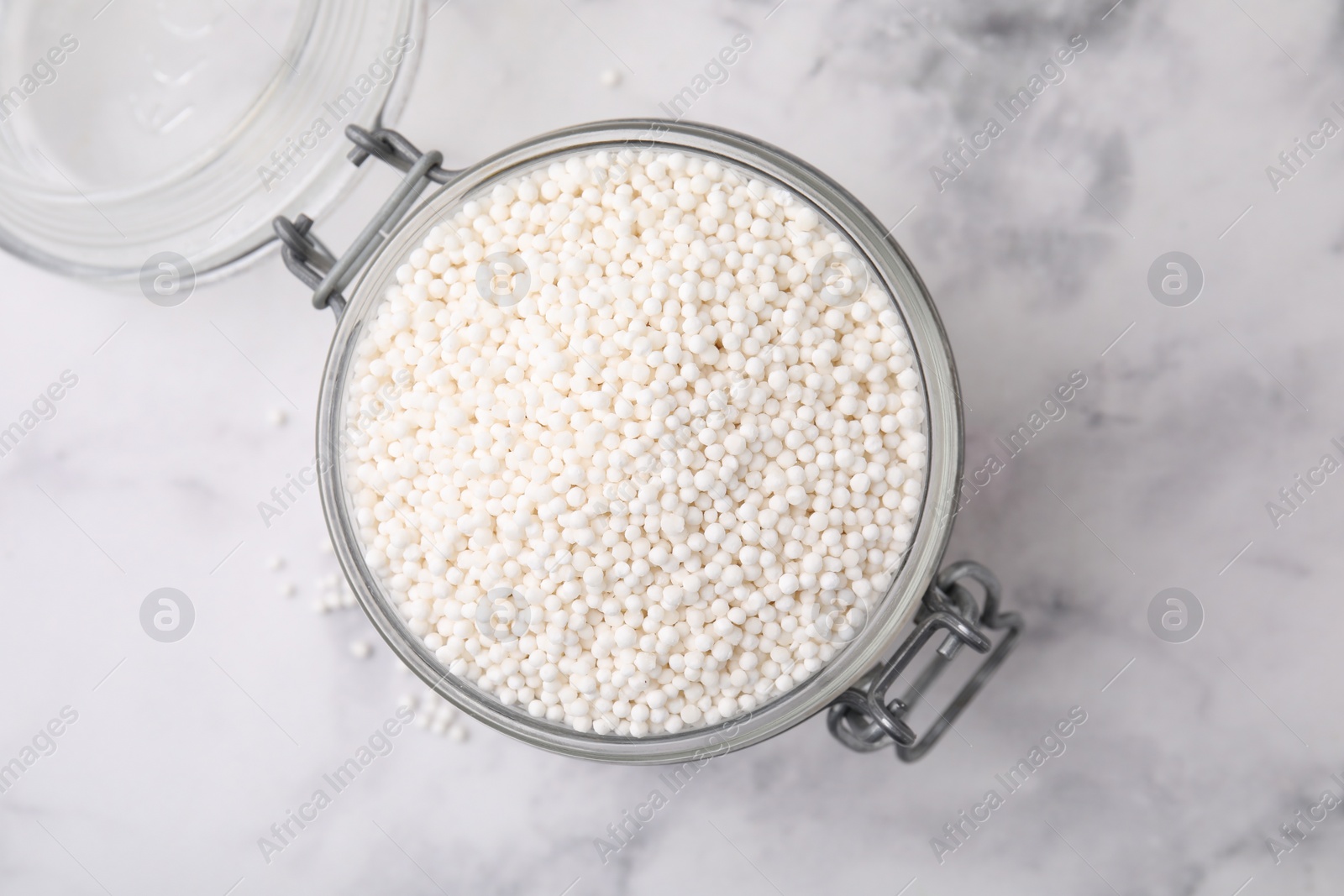 Photo of Tapioca pearls in jar on white marble table, top view